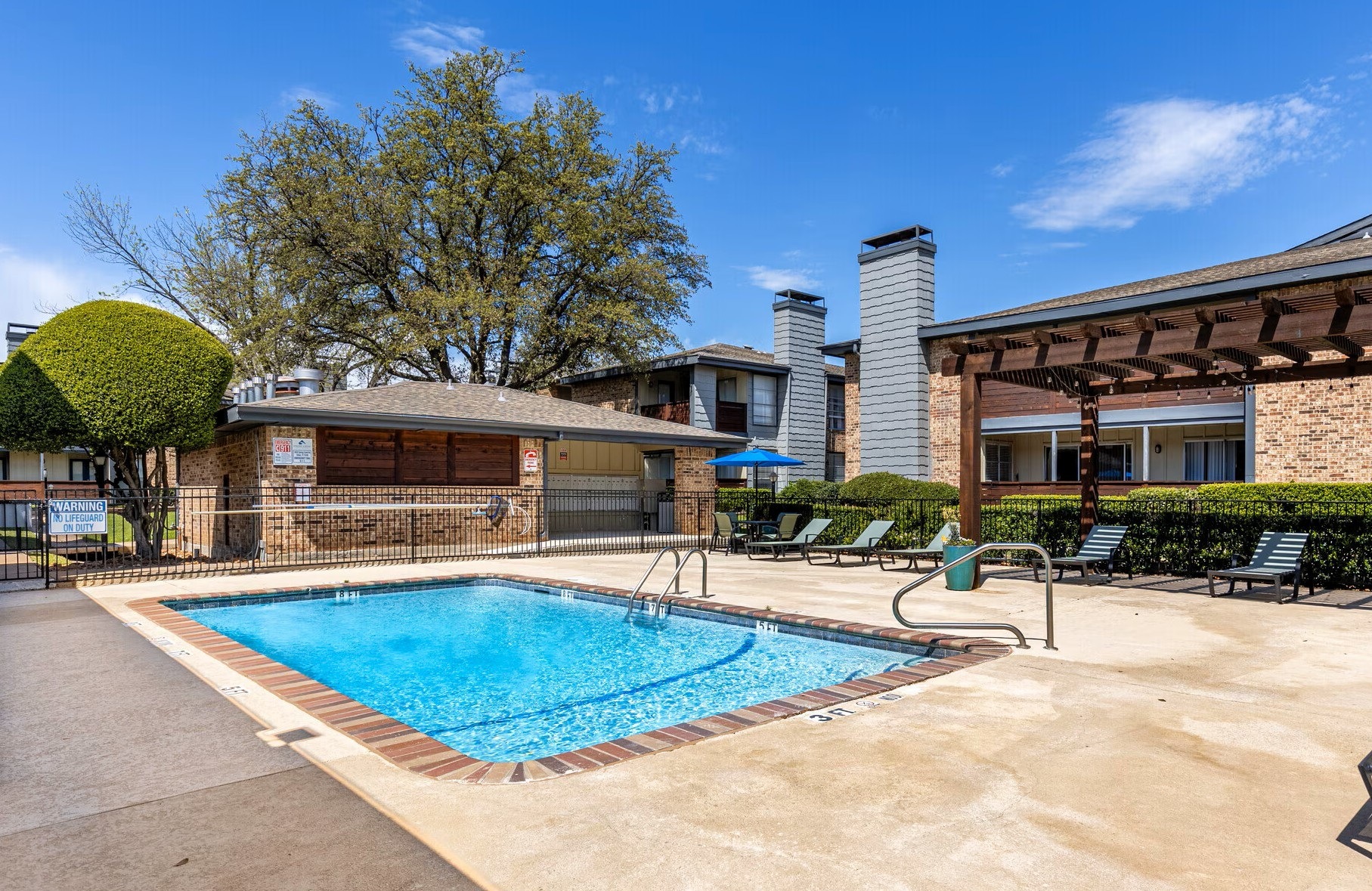 A swimming pool surrounded by a concrete patio and a small building.