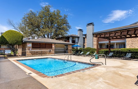 A swimming pool surrounded by a concrete patio and a small building.