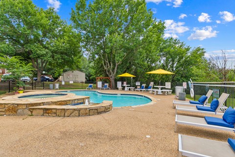 A pool surrounded by trees and chairs.
