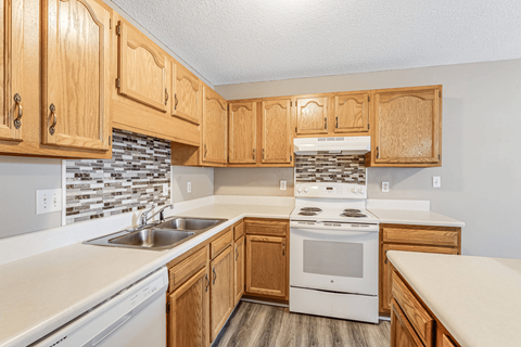 A kitchen with wooden cabinets and a white stove top oven.