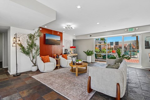 A living room with a couch, a chair, a table, a potted plant, and a painting on the wall.