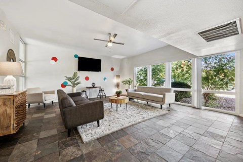 A living room with a brown couch and a flat screen TV mounted on the wall.