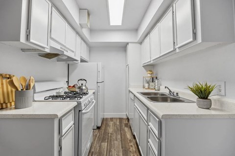 A kitchen with white cabinets and a wooden floor.