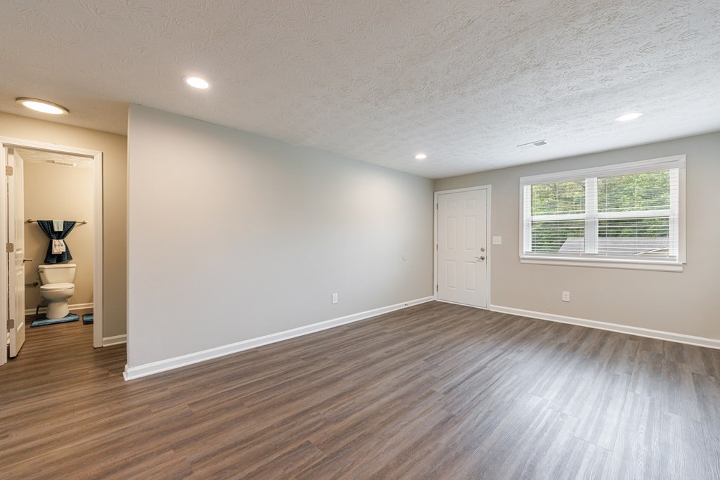 A room with wooden flooring and a window with blinds.