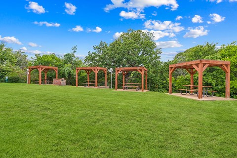 A row of wooden pavilions are set in a grassy field.
