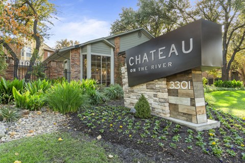 A sign that says "Chateau on the River" in front of a building.
