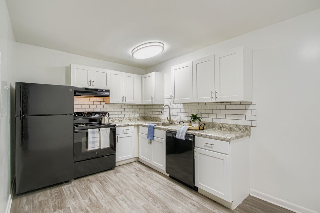 A kitchen with black appliances and white cabinets.