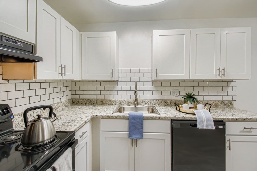 A kitchen with white cabinets and a black stove top.