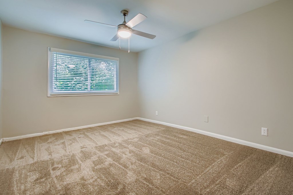 A room with a ceiling fan and a window with blinds.