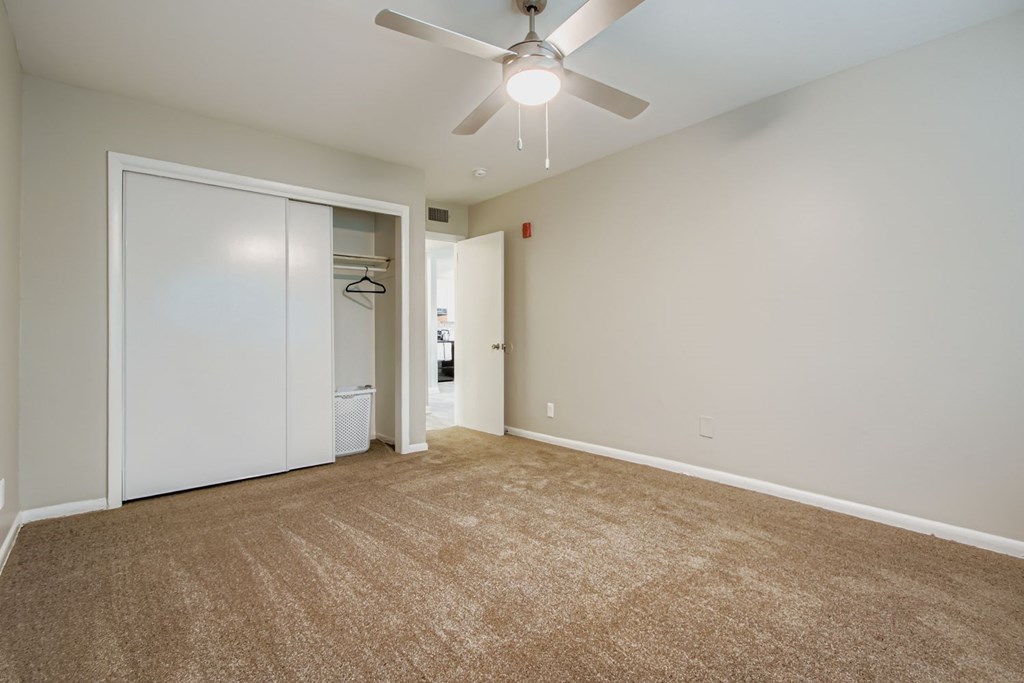 A room with a carpeted floor and a ceiling fan.