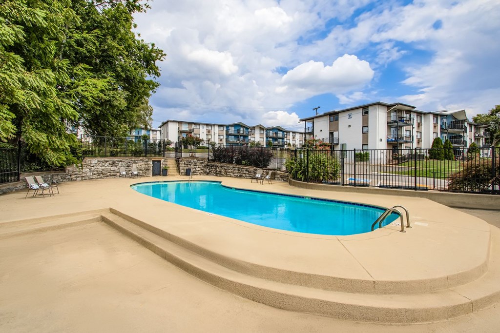 A swimming pool surrounded by a concrete deck and a fence.