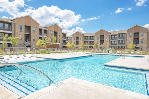 A large swimming pool in front of apartment buildings.