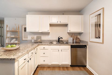 A kitchen with white cabinets and a granite countertop.