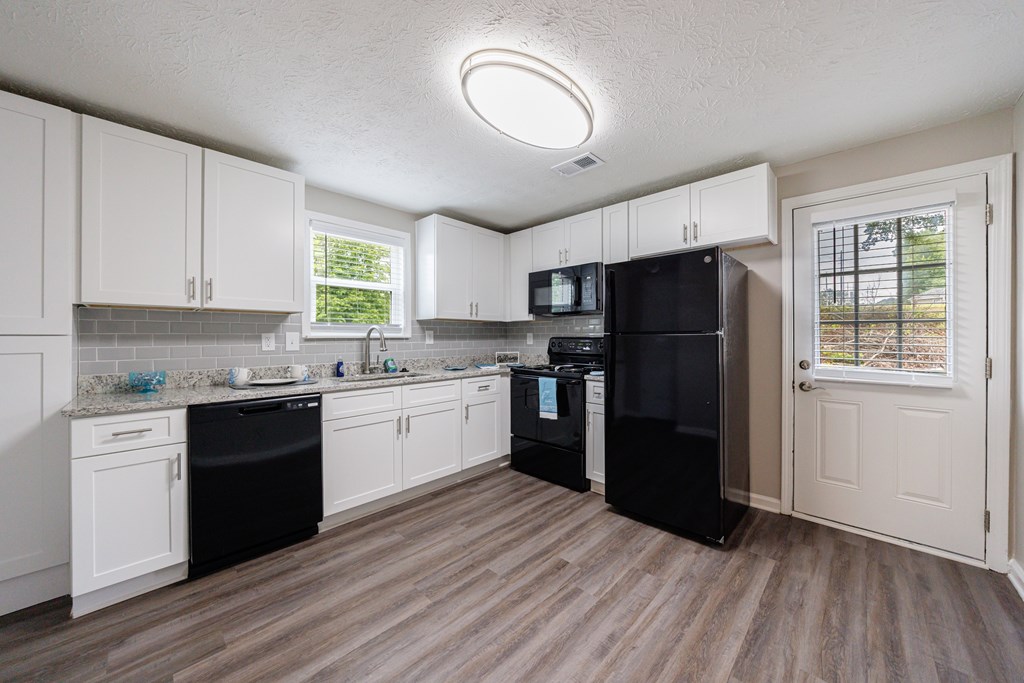 A kitchen with black appliances and white cabinets.