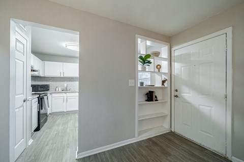 A kitchen with white cabinets and a white door.