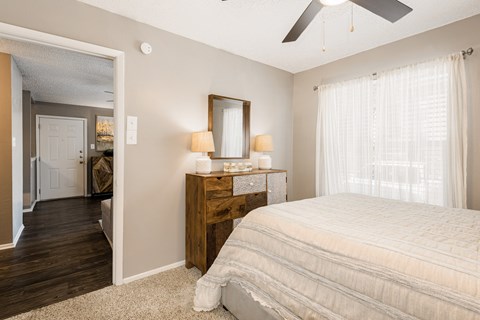 A bedroom with a large bed, a dresser with a mirror, and a ceiling fan.