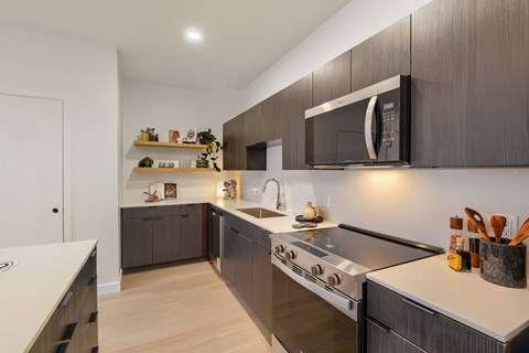 A modern kitchen with dark wood cabinets and stainless steel appliances.