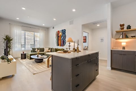 A modern kitchen with a large island and a living room with a sofa and a coffee table.
