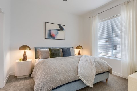 A bedroom with a large bed and two lamps.