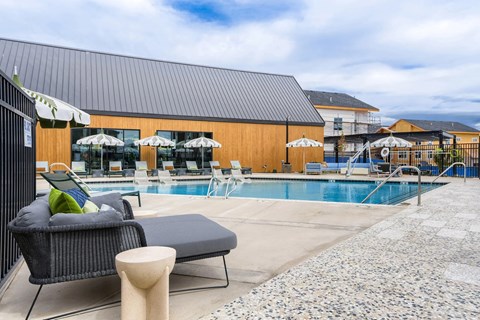A pool area with a black sofa and a table.
