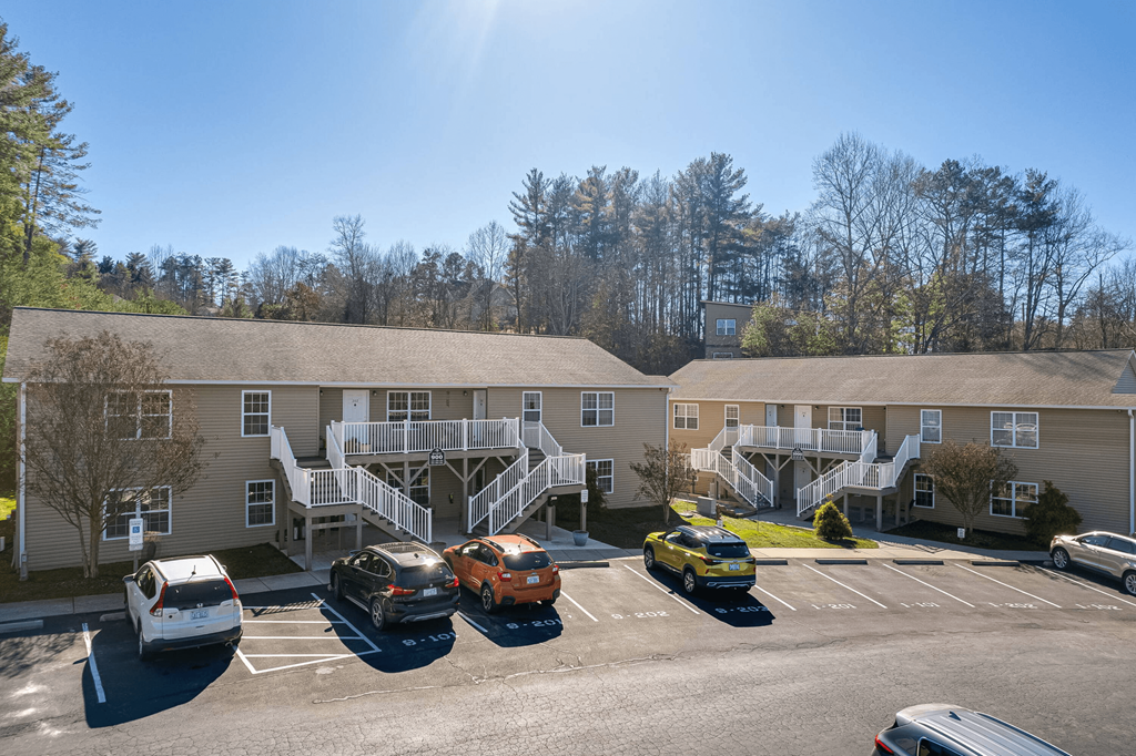 a parking lot with cars in front of an apartment building