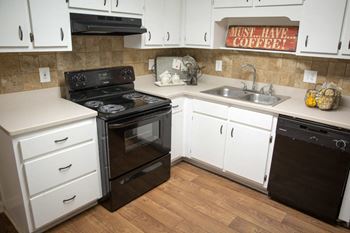 a kitchen with white cabinets and black appliances