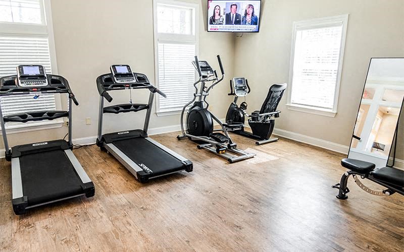 a gym with exercise equipment on a wood floor