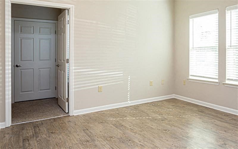 an empty living room with a white door and wood floors