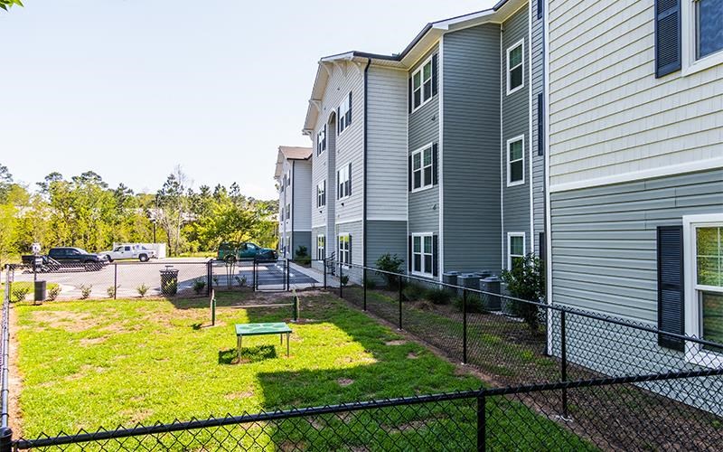 a fenced in yard in front of an apartment building