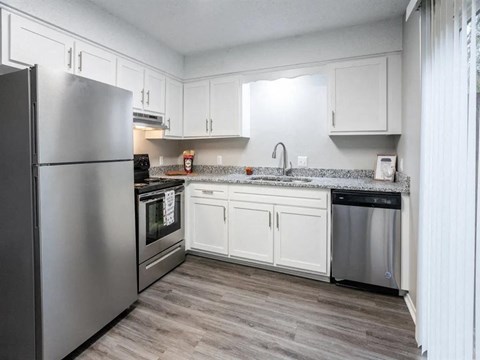 A kitchen with a refrigerator, oven, and sink.