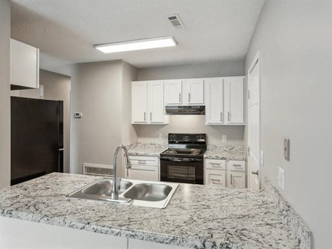 A kitchen with granite countertops and white cabinets.