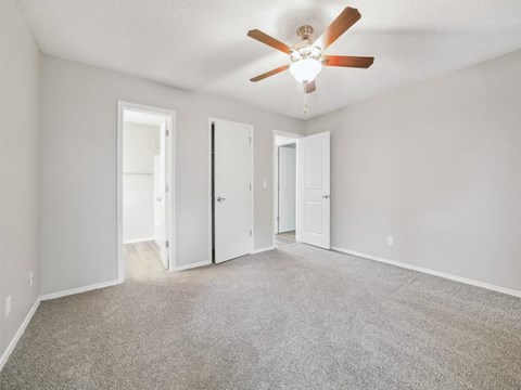 A room with a ceiling fan and carpeted floor.