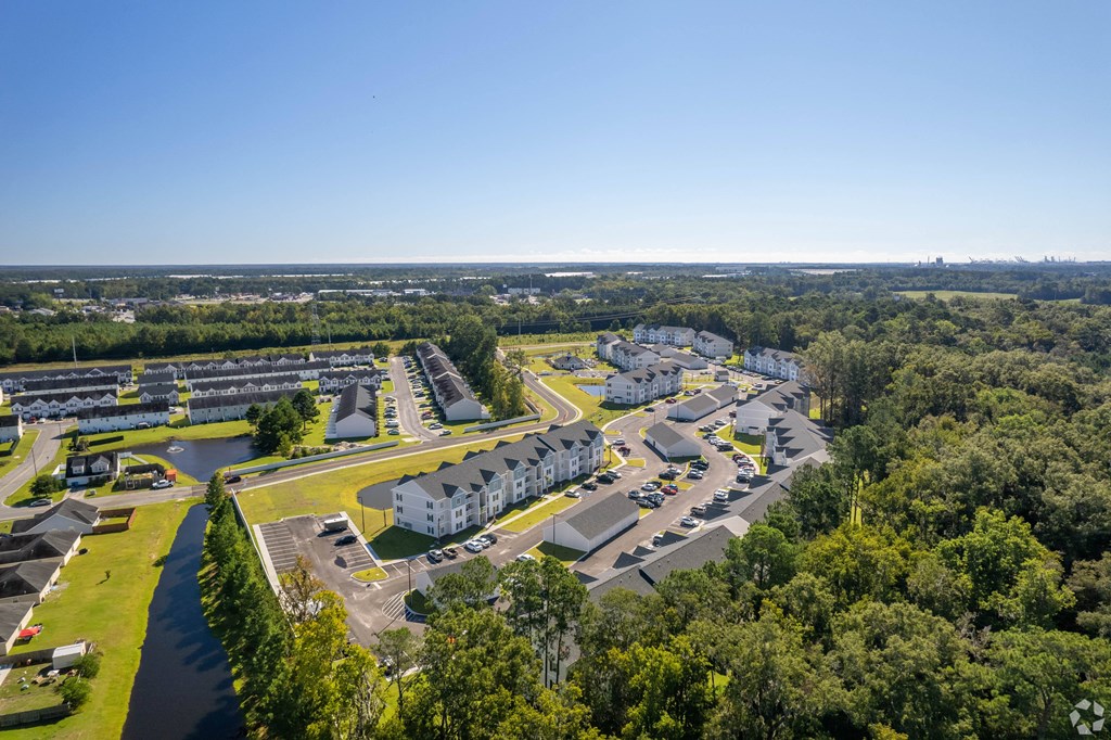 an aerial view of a parking lot with houses and trees