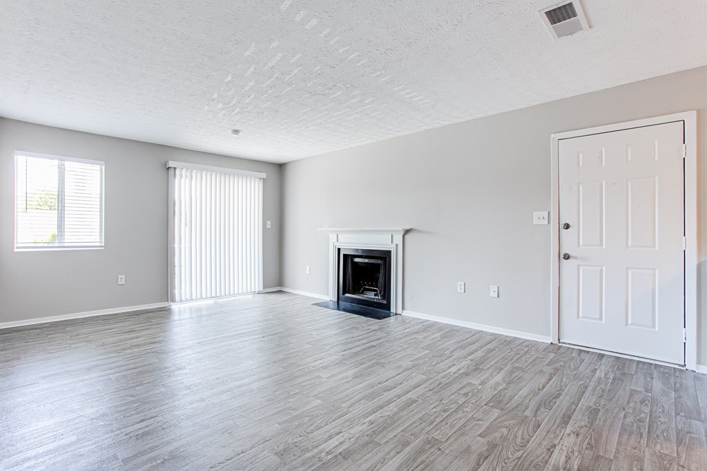 A spacious living space with fireplace, wood-like flooring and large windows at Ascend at Stone Mountain apartments. Stone Mountain, GA 30088.
