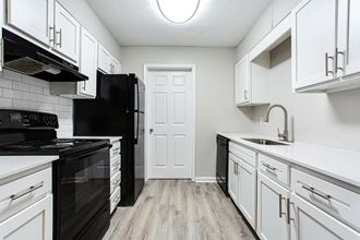 Spacious kitchen with white cabinets and black appliances at