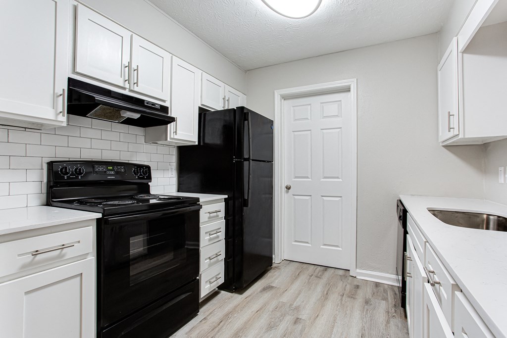Modern kitchen with white cabinets, black fridgerator and black stove Ascend at Stone Mountain apartments. Stone Mountain, GA 30088.