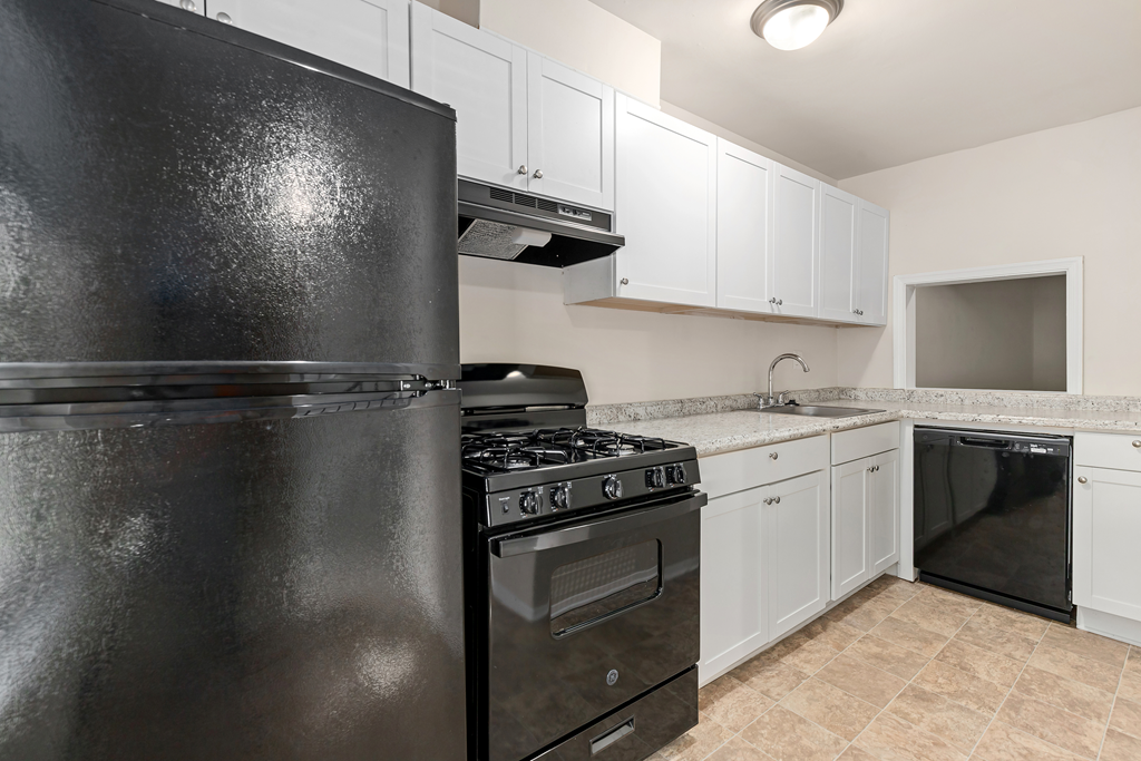 a kitchen with white cabinets and black appliances
