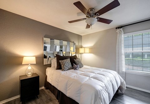 A bedroom with a bed, a ceiling fan, and a window with blinds.