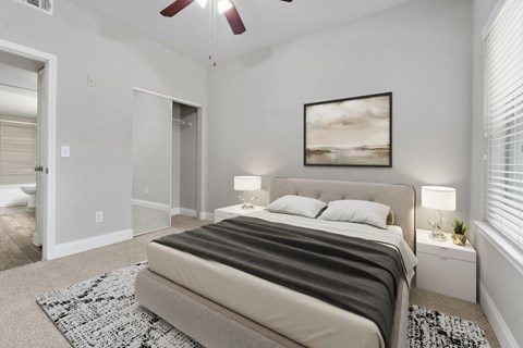 A bedroom with a large bed and a ceiling fan.