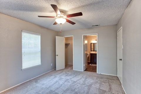 A room with a ceiling fan and carpeted floor.