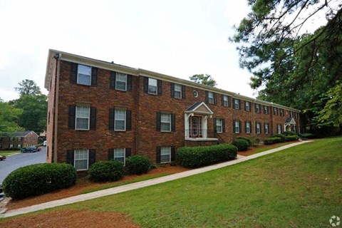 a red brick apartment building with a sidewalk and grass