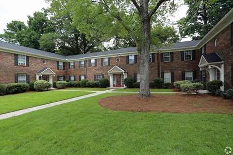 the front yard of a brick house with a tree in the yard