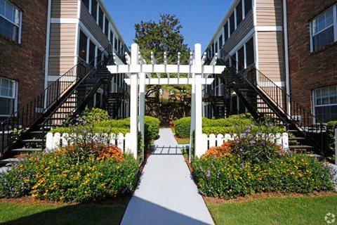a white gate in a garden in front of an apartment building