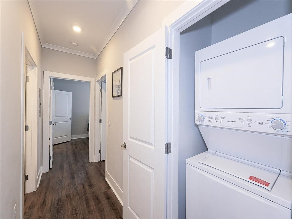 a laundry room with a washer and dryer and a hallway to a bedroom