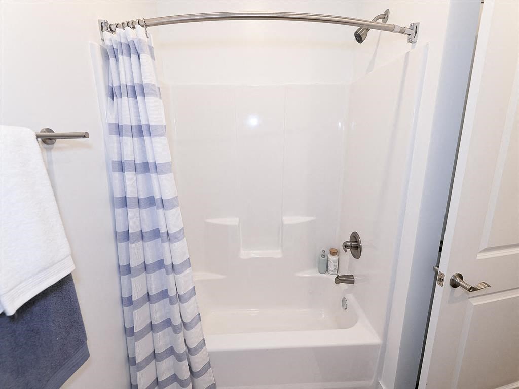 a bathroom with a shower and a blue and white shower curtain