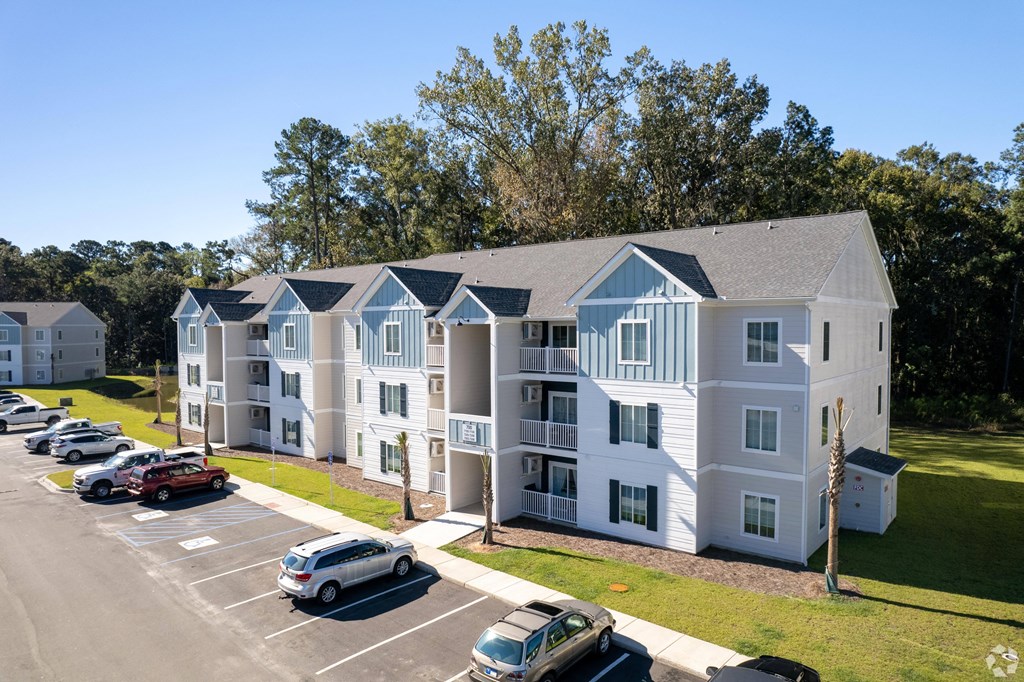 an aerial view of an apartment building with cars parked in a parking lot