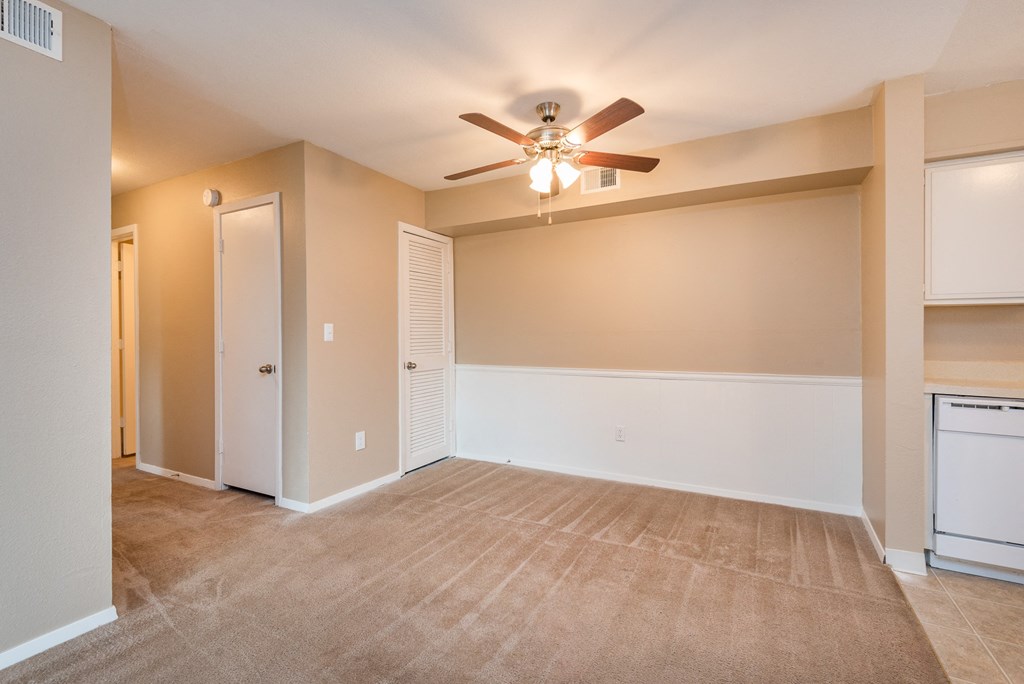 an empty living room with a ceiling fan