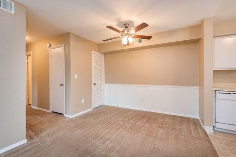 an empty living room with a ceiling fan