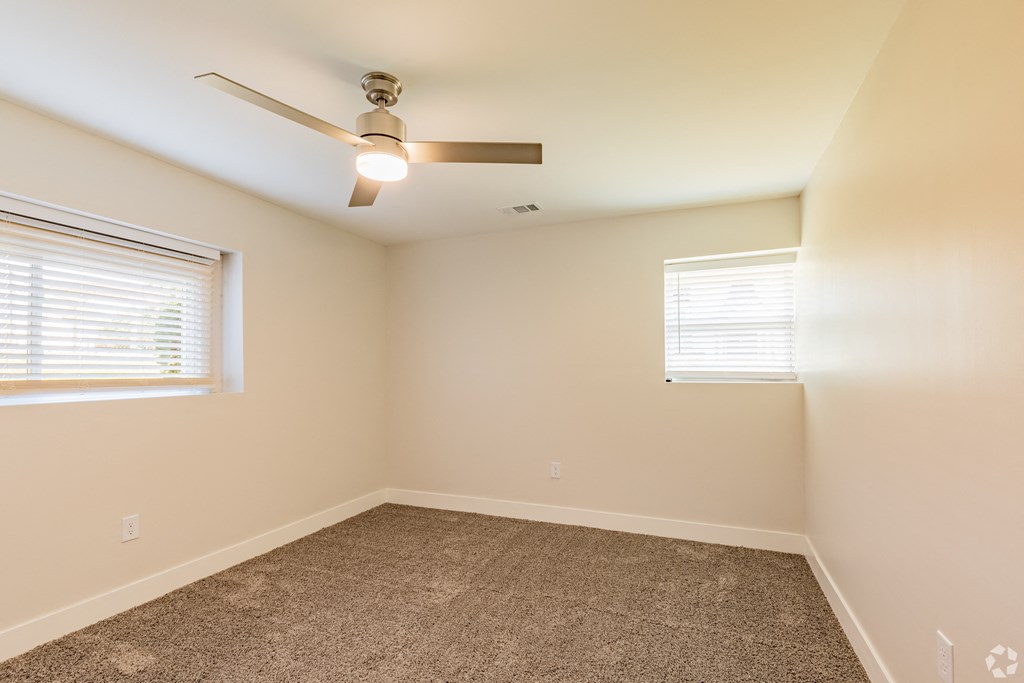 a bedroom with two windows and a ceiling fan