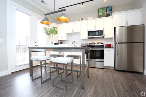 a kitchen with stainless steel appliances and a bar with three stools at Century Baxter Avenue, Louisville, 40204